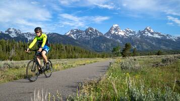 A cyclist on a paved path with a mountainous backdrop.