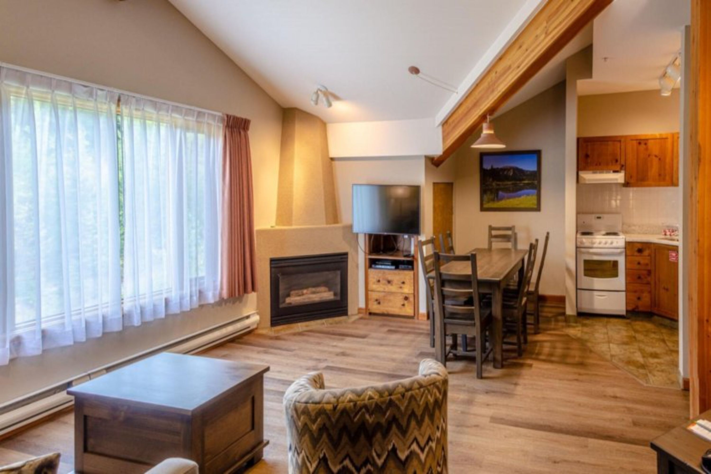 Una sala de estar con chimenea, un comedor y una cocina con armarios de madera y estufa.