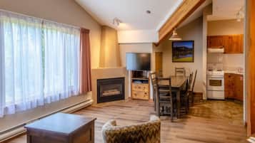 Una sala de estar con chimenea, un comedor y una cocina con armarios de madera y estufa.