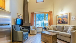 Una sala de estar moderna con un sofá, sillones, una mesa de centro, un televisor y una chimenea.