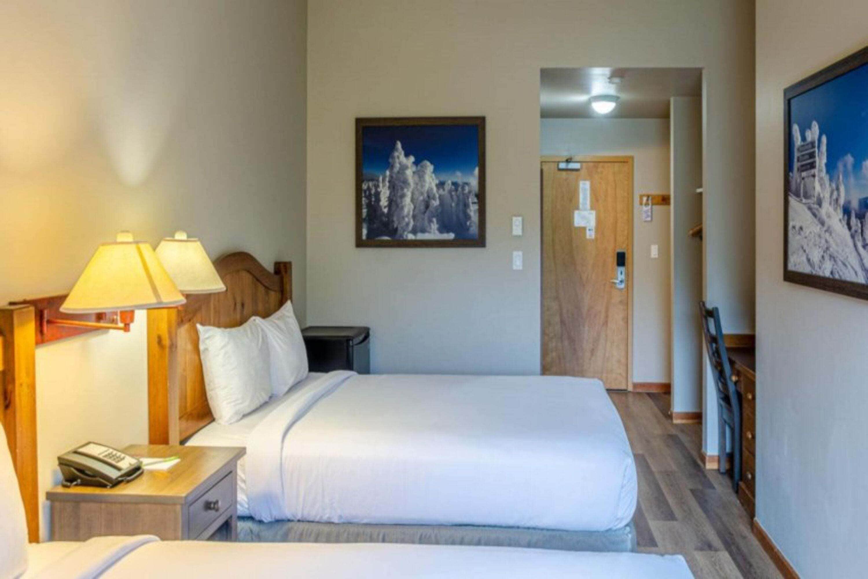 A hotel room with a bed, bedside lamps, a nightstand, a telephone, and a framed picture on the wall.