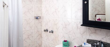 A bathroom with a shower, toilet, sink, and a mirror.