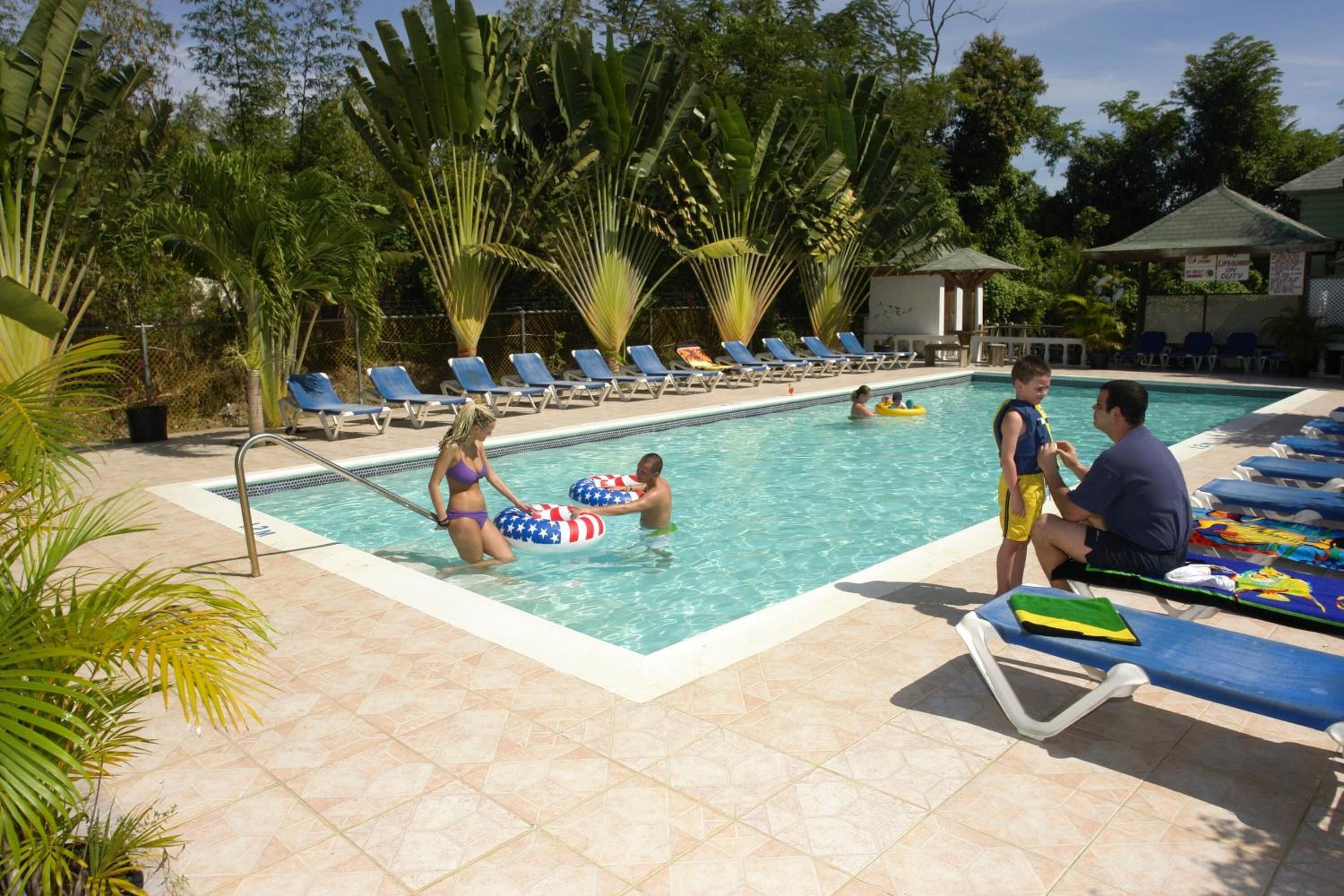 A swimming pool with lounge chairs and palm trees.