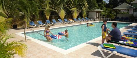 A swimming pool with lounge chairs and palm trees.
