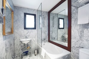 A modern bathroom with a marble wall, a large mirror, a bathtub, and a sink. - Hotel Caribou (Pas de la Casa)