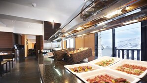 A buffet area with various food options, a seating area, and a view of the mountains. - Hotel Caribou (Pas de la Casa)