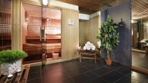 Uma sala de sauna com paredes de madeira, porta de vidro, um banco de madeira e um vaso de planta.
