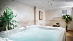 A spa room with a hot tub, potted plants, and a tiled wall. - Hotel Caribou (Pas de la Casa)