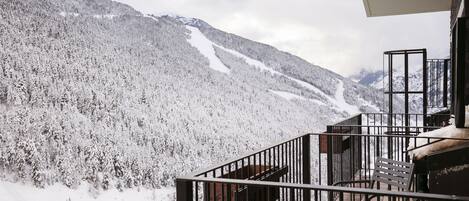 A balcony with a view of a snow-covered mountain and a ski slope.