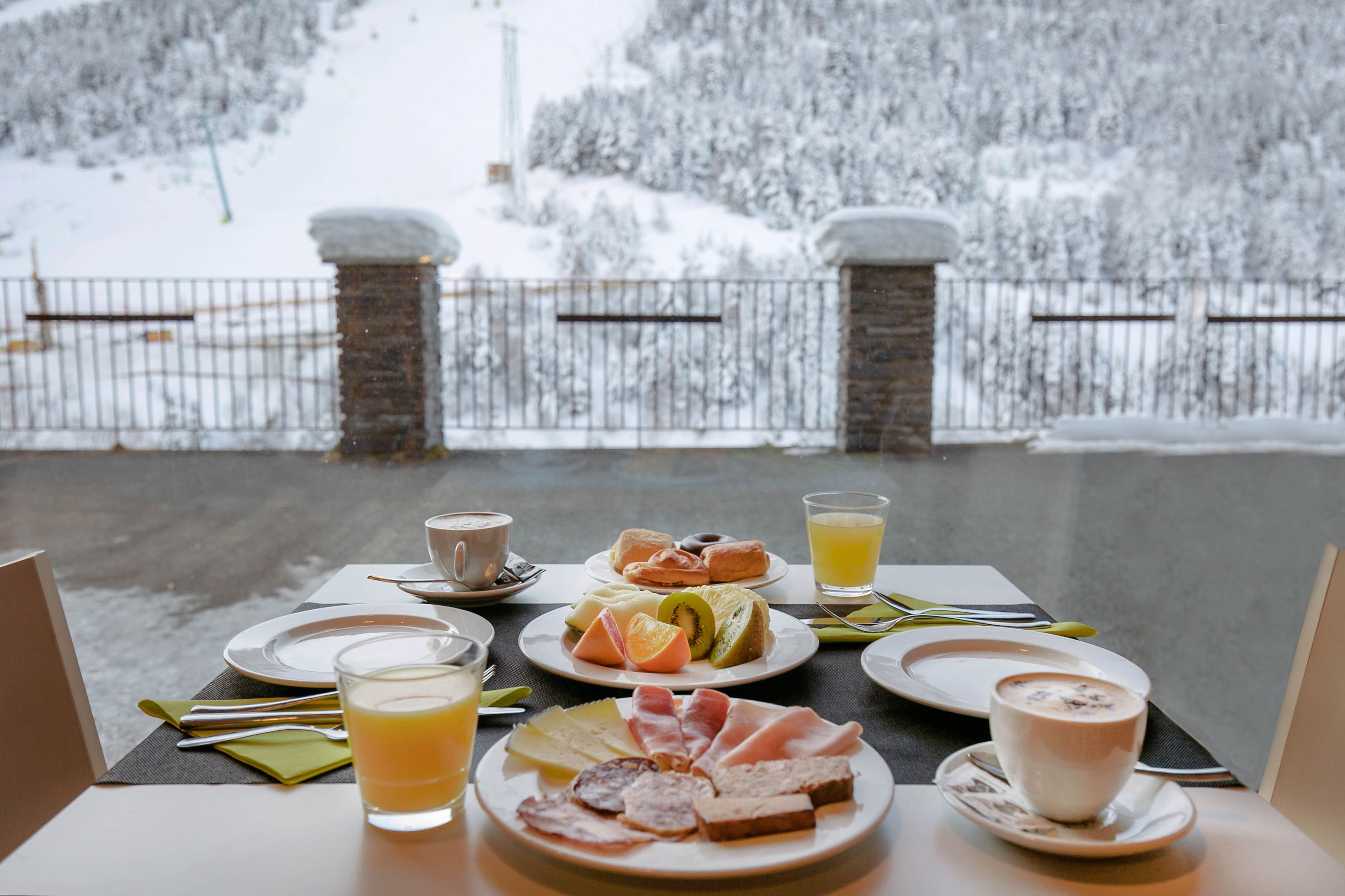 A breakfast table with plates of food, a cup of coffee, and a glass of orange juice.