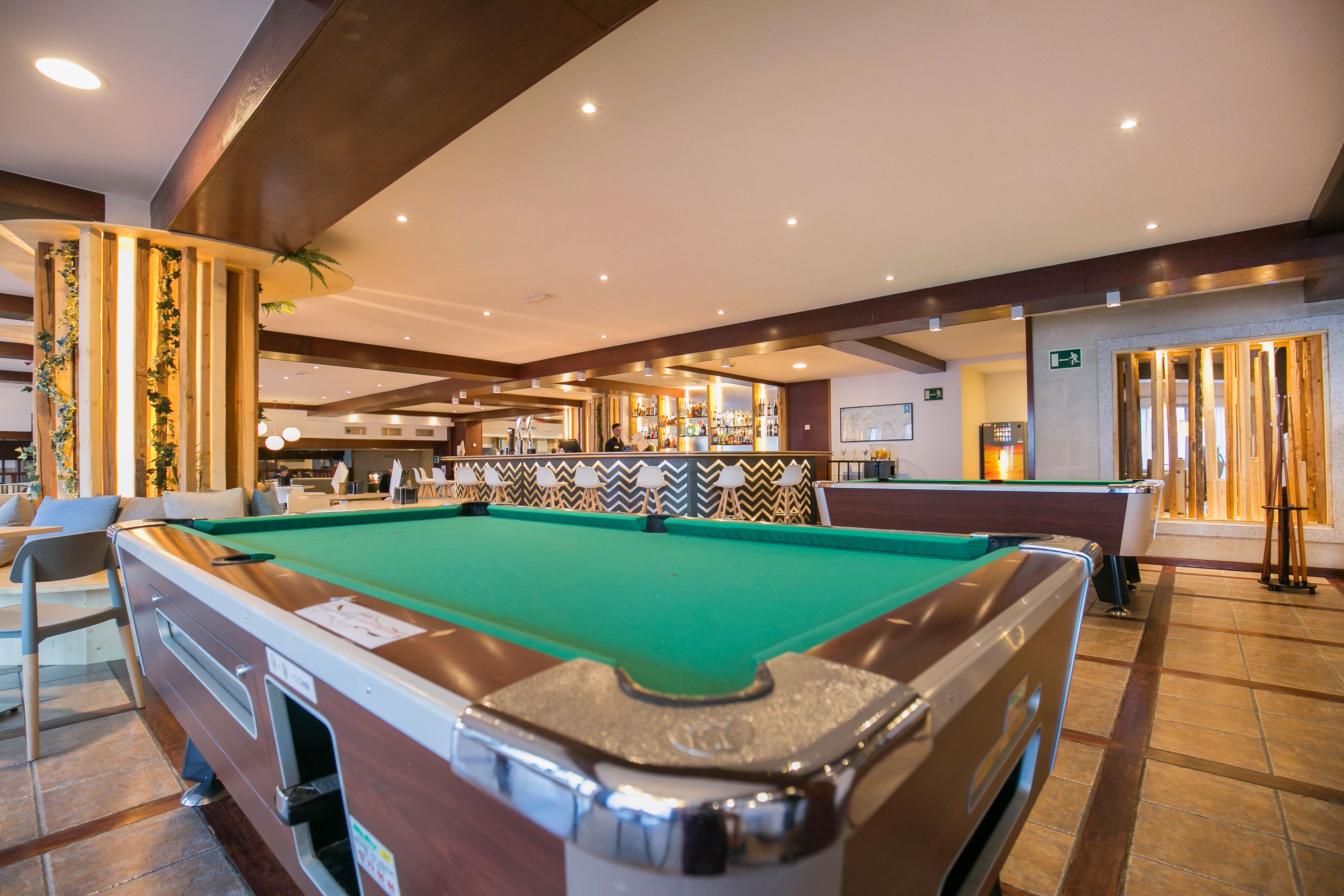 A pool table in a well-lit indoor area with a bar in the background.