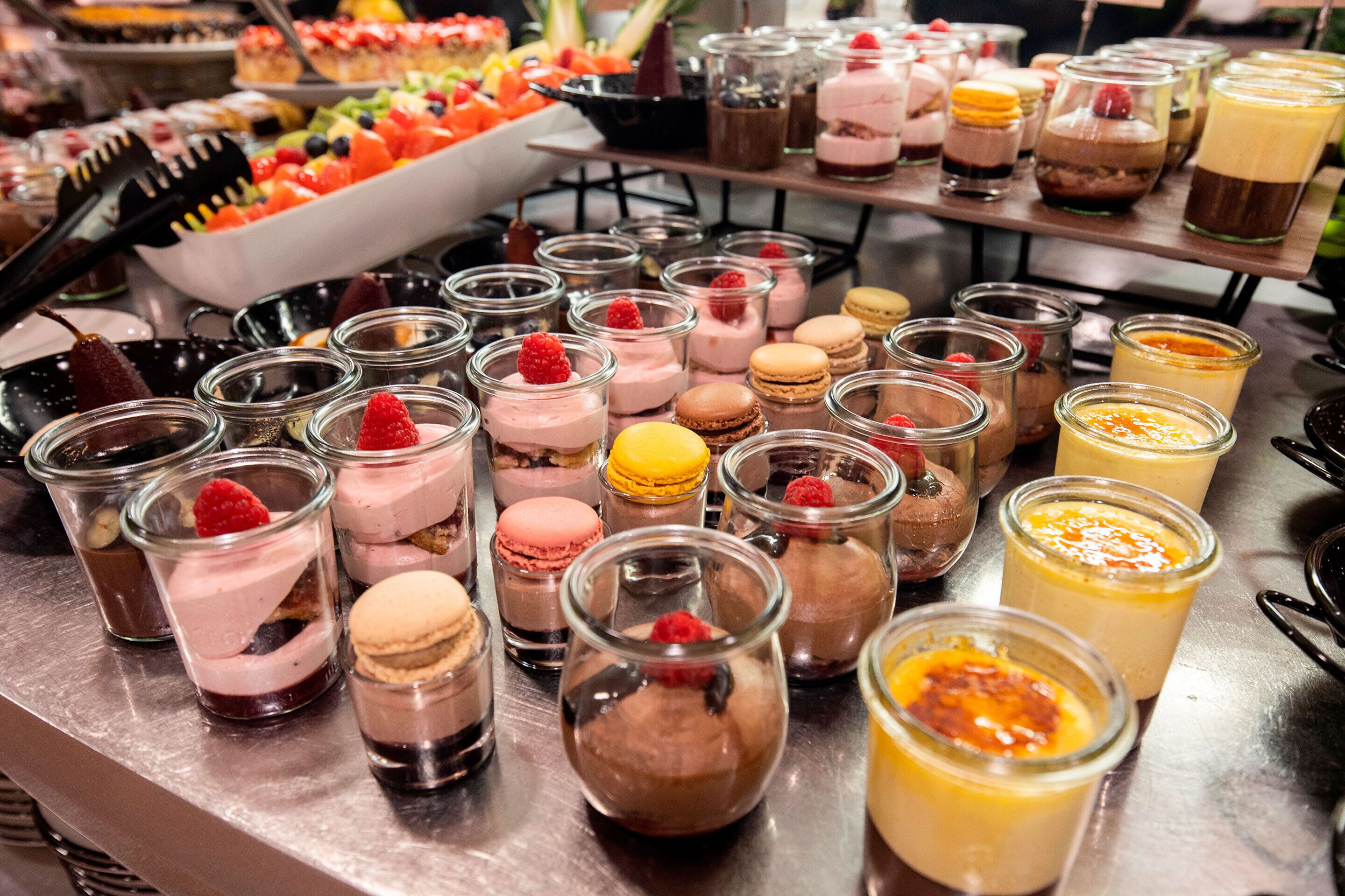 Una variedad de postres, incluyendo macarons, mousse de chocolate y postres con fruta, dispuesta en una mesa buffet.