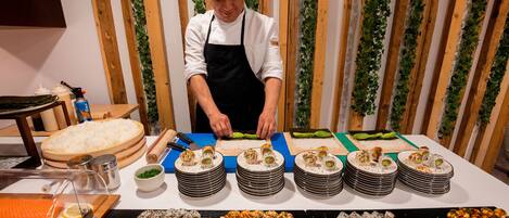 A chef preparing sushi at a counter with various sushi dishes and ingredients.