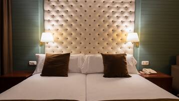 A double bed with a tufted headboard, two bedside lamps, and a bedside phone.