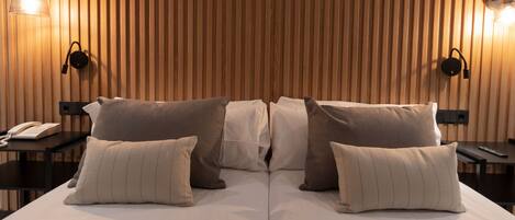 A hotel room with a wooden slat wall, two bedside tables with lamps, and a bed with multiple pillows.