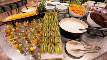 A buffet with various food items including fruits, desserts, and beverages.