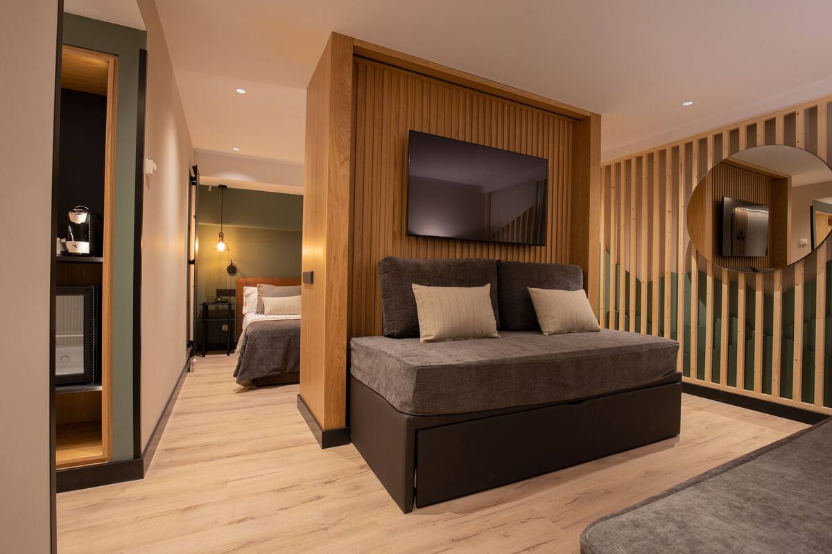 A modern bedroom with a large bed, a TV mounted on the wall, and a wooden panel design.