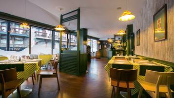 Een restaurant met meerdere tafels en stoelen, houten vloeren en hangende吊灯.