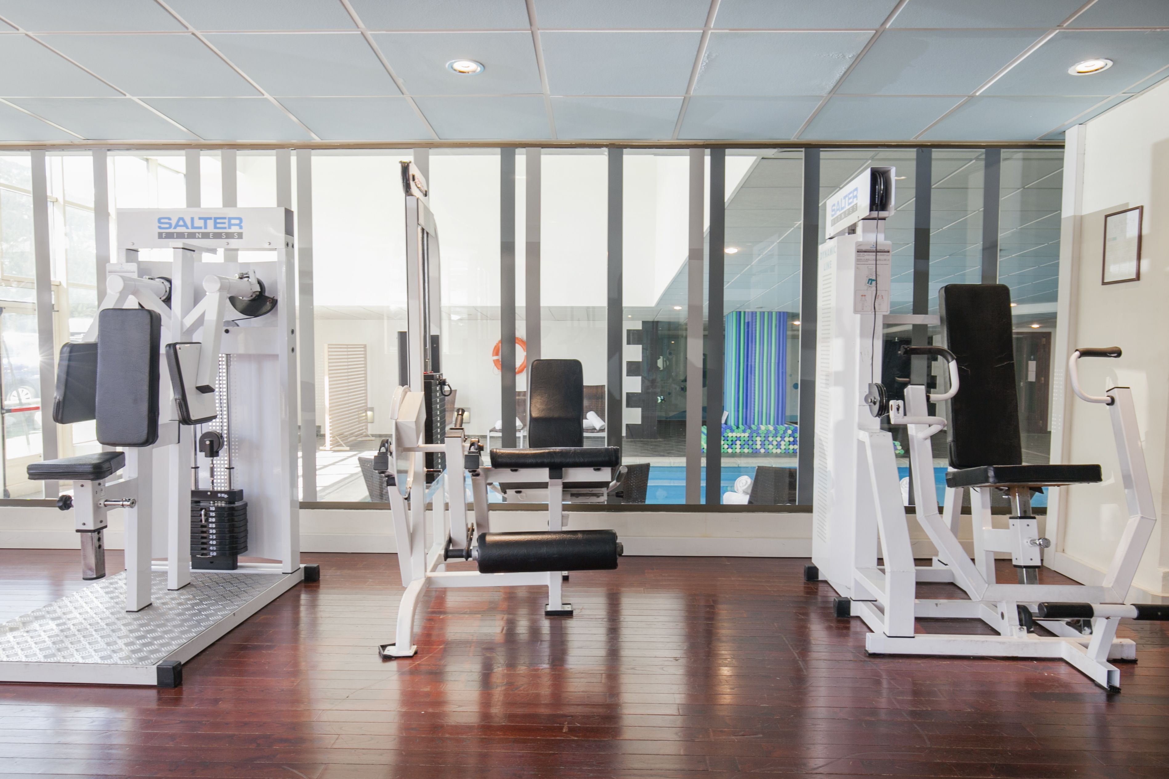 Un gimnasio con equipamiento Salter Fitness, amplias ventanas y suelo de madera.