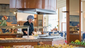 Disposición de bufé con un chef preparando alimentos, un rebozo de azulejos y diversos platillos expuestos en la barra.