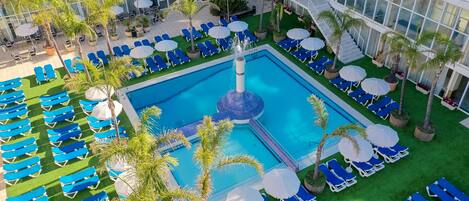 Una piscina al aire libre, sombrillas, sillones reclinables de piscina