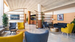 Un lobby moderno con zonas de estar, un mostrador de recepción y un bar.