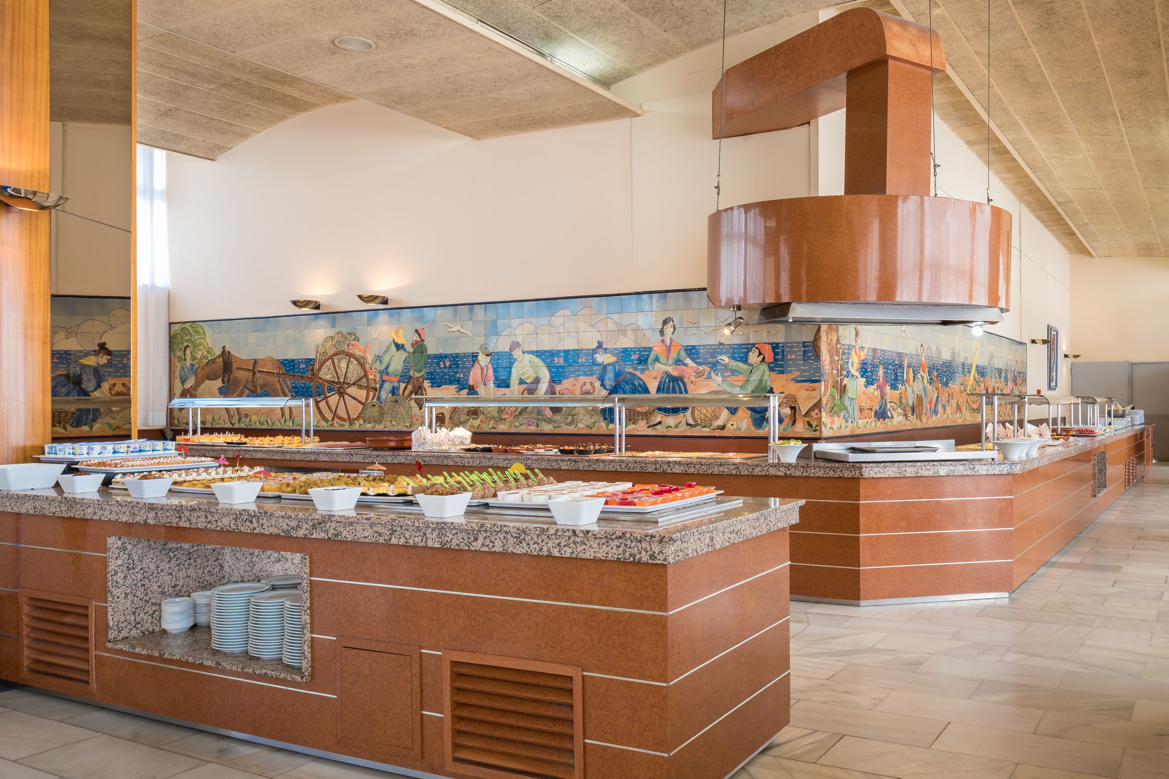 A buffet area with a large mural, granite counters, and a copper range hood.