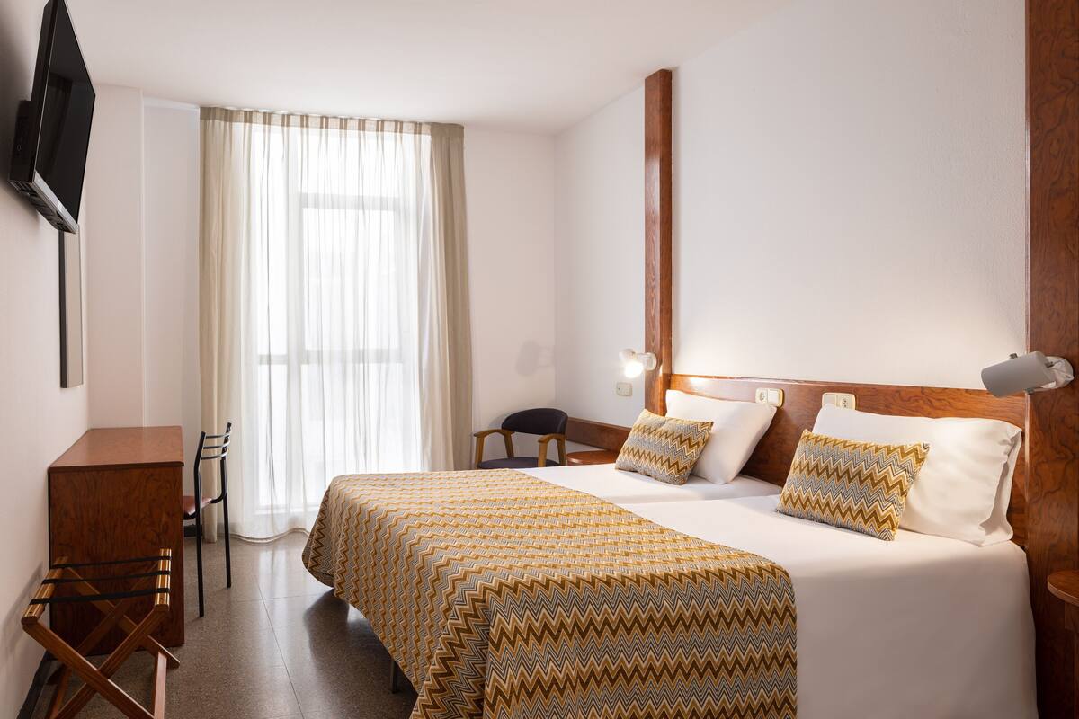 Hotellihuone, jossa on sänky, työpöytä ja tuoli.