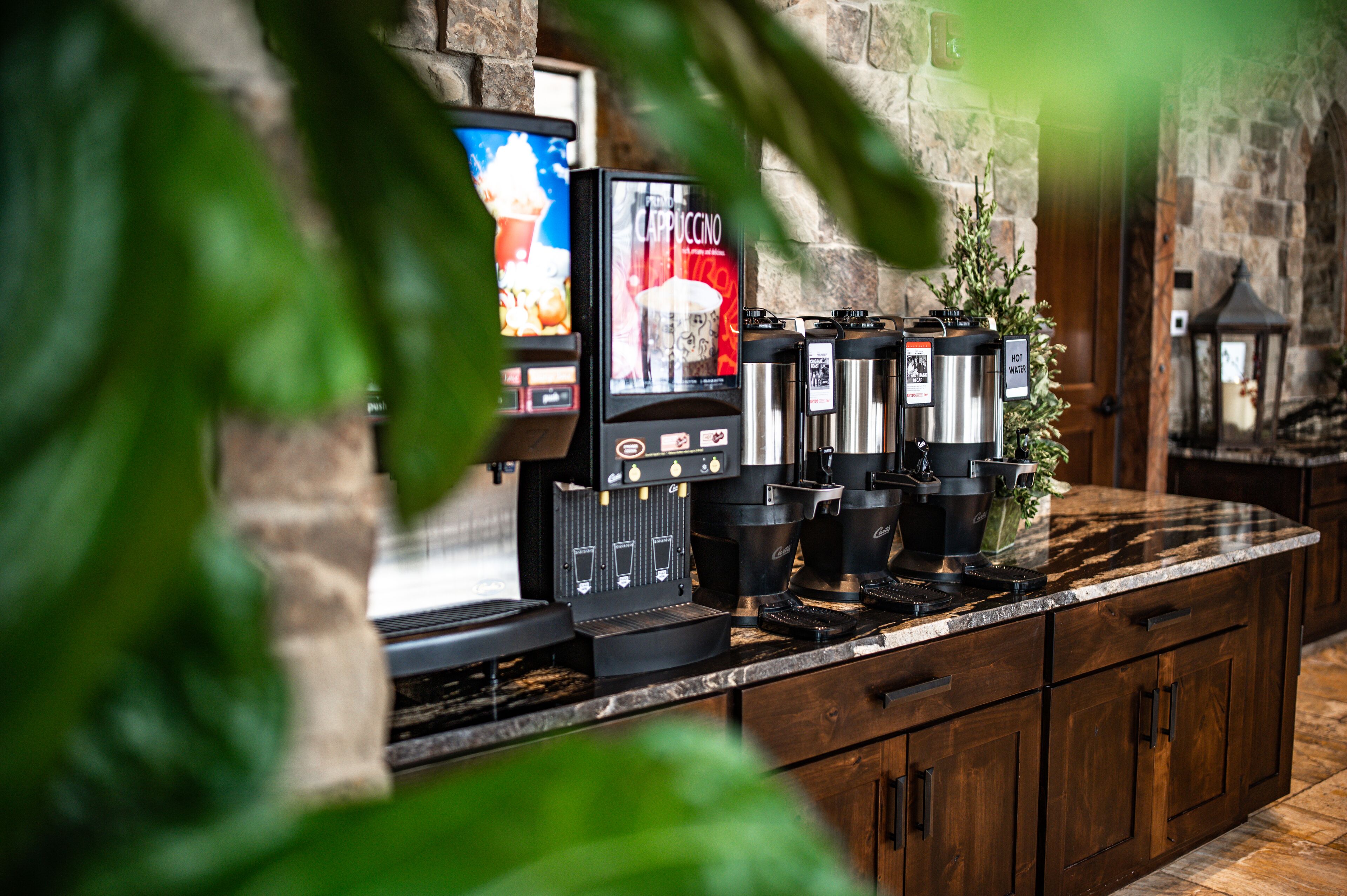 Un espace dédié au café, équipé de plusieurs machines à expresso et d’un écran numérique affichant le menu des différentes variétés de café.