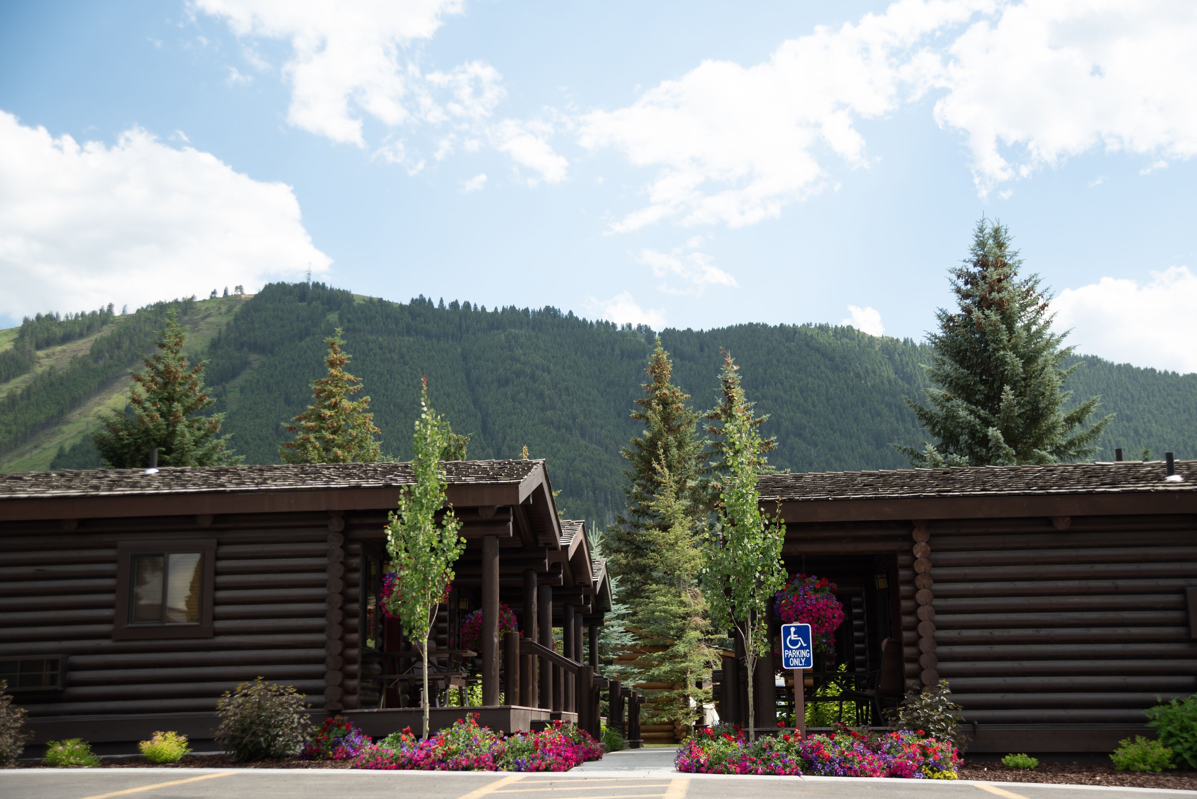 Un bâtiment de style chalet en bois, doté d’un espace de stationnement et surplombant un paysage montagneux.
