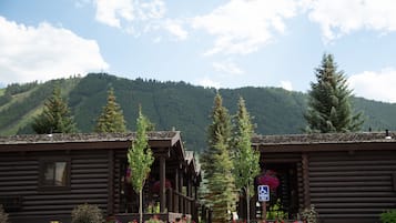 Un bâtiment de style chalet en bois, doté d’un espace de stationnement et surplombant un paysage montagneux.