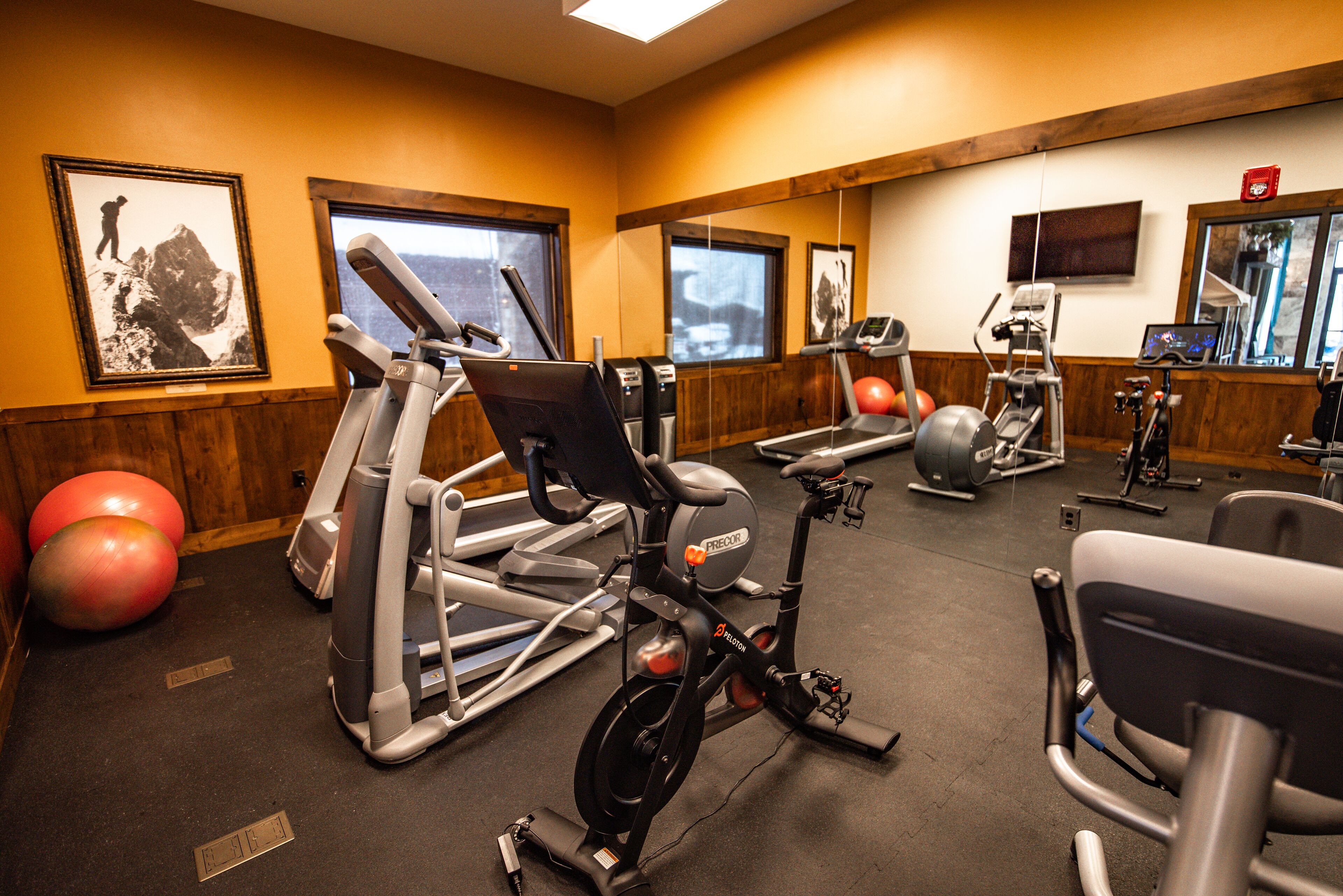 Ein Fitnessstudio mit verschiedenen Trainingsgeräten, darunter Laufbänder und Ergometer sowie Trainingsbälle.