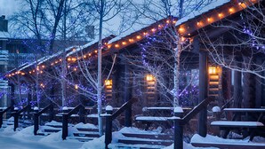A snow-covered outdoor area with wooden benches and steps leading to a building with string lights. - Elk Country Inn (Jackson)