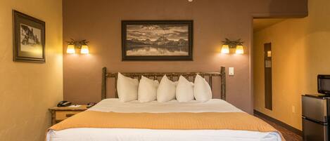 A hotel room with a large bed, a nightstand, a television, and a framed picture on the wall.