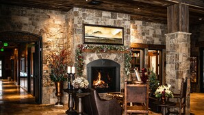 A lobby with a stone fireplace, a mounted painting, and a wooden reception desk. - Elk Country Inn (Jackson)