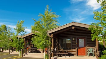 Ein rustikales Blockhaus mit Veranda, Picknicktischen und einem Parkplatz.