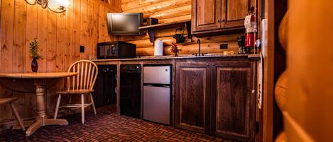 Un interior de madera con una zona de cocina que incluye un microondas, un refrigerador y armarios de madera.