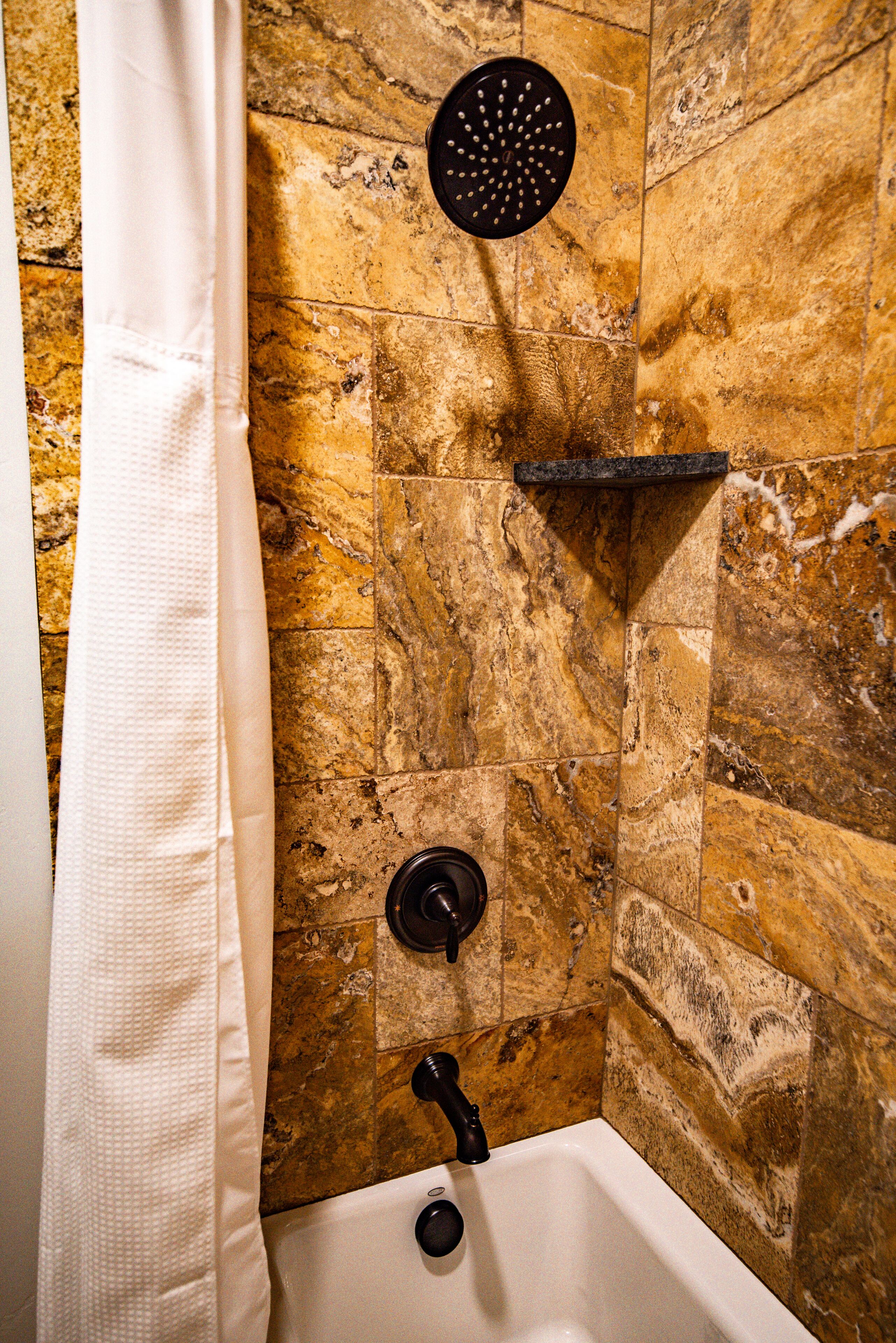 A bathroom with a bathtub, a showerhead, and a towel rack.