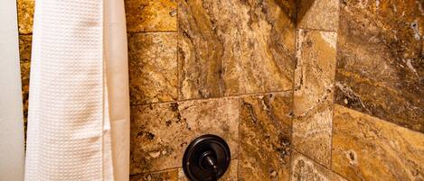 A bathroom with a bathtub, a showerhead, and a towel rack.