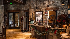 A stone-walled reception area with a wooden counter, framed pictures, and a clock on the wall. - Elk Country Inn (Jackson)