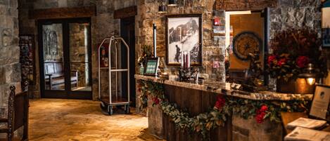 A stone-walled reception area with a wooden counter, framed pictures, and a clock on the wall.