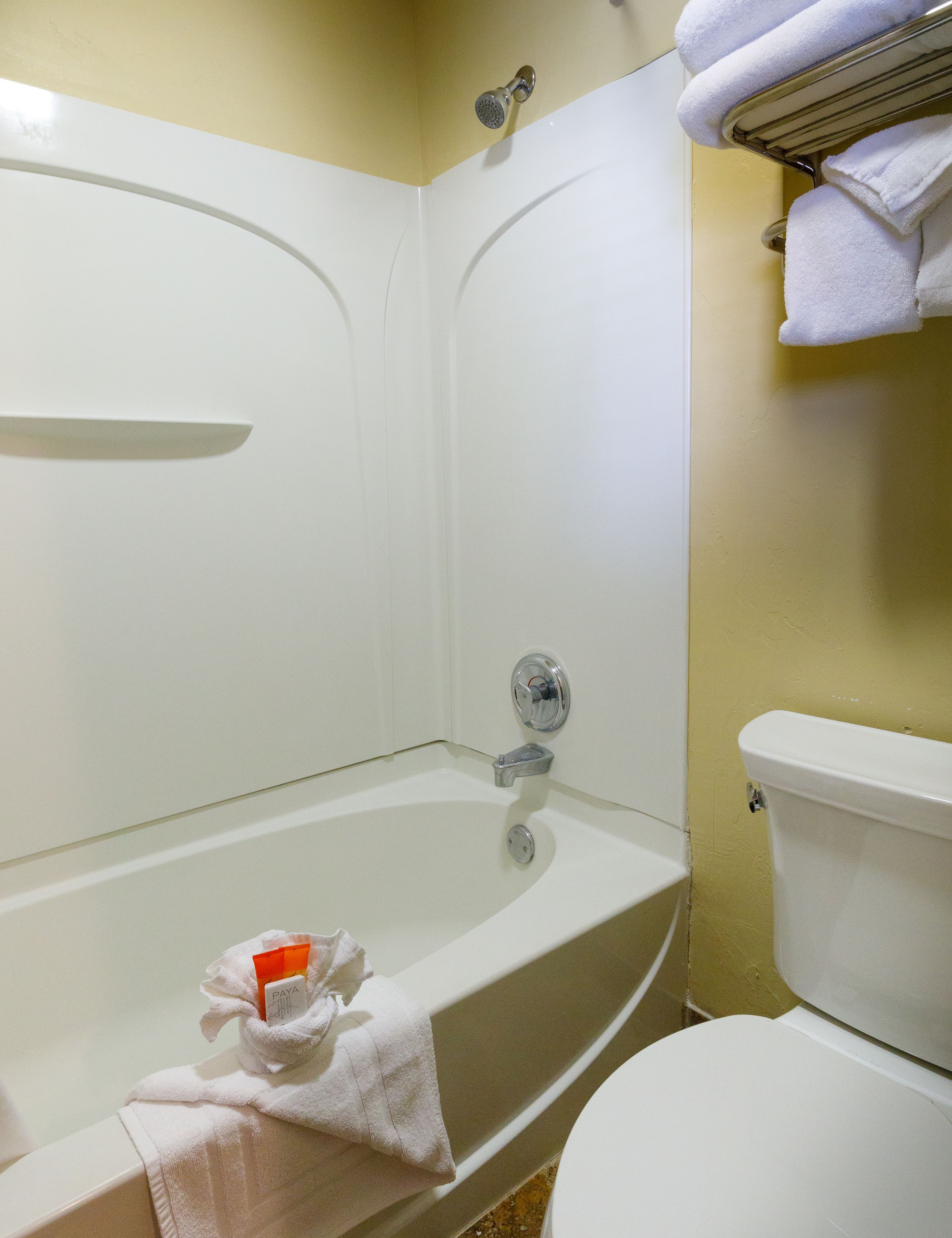 Een badkamer met een bad, toilet en een handdoekrek met handdoeken.
