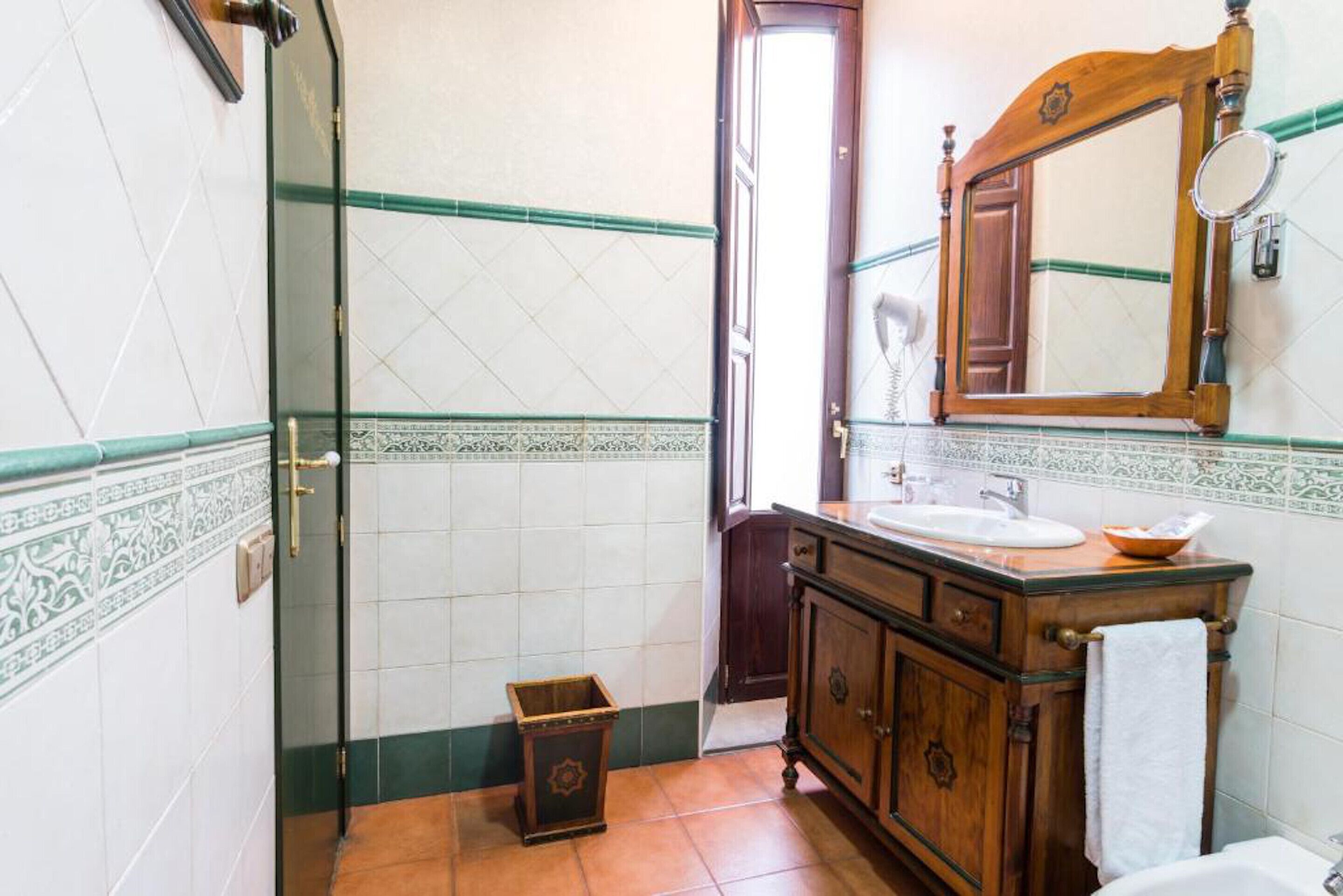 Un baño con tocador de madera, un espejo y un lavabo.