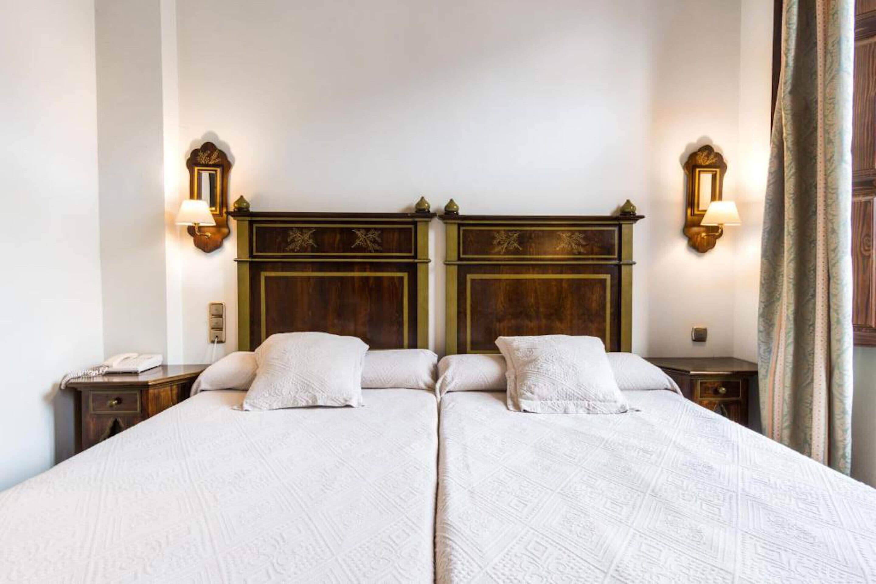 Una cama doble con cabecera de madera, dos mesitas de noche y lámparas fijadas a la pared.