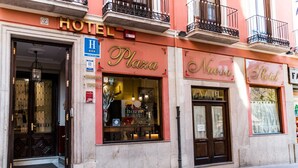 A hotel facade with 'Hotel Plaza' and 'Nuova Hotel' signage, a visible entrance, and a 'H' handicap accessibility sign.