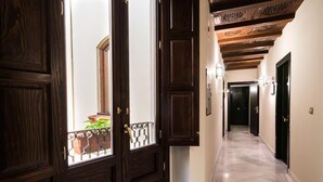 A hallway with dark wooden doors, a marble floor, and a view of a balcony with plants.