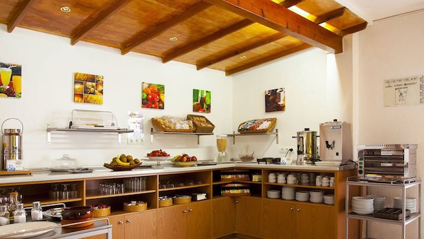 Una cocina con armarios de madera, una cafetera y diferentes alimentos sobre la encimera.