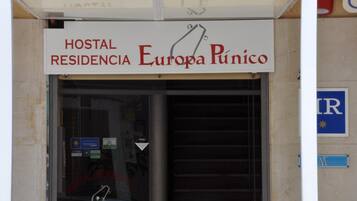 A sign for "Hostal Residencia Europa Púnico" with a closed shutter door.