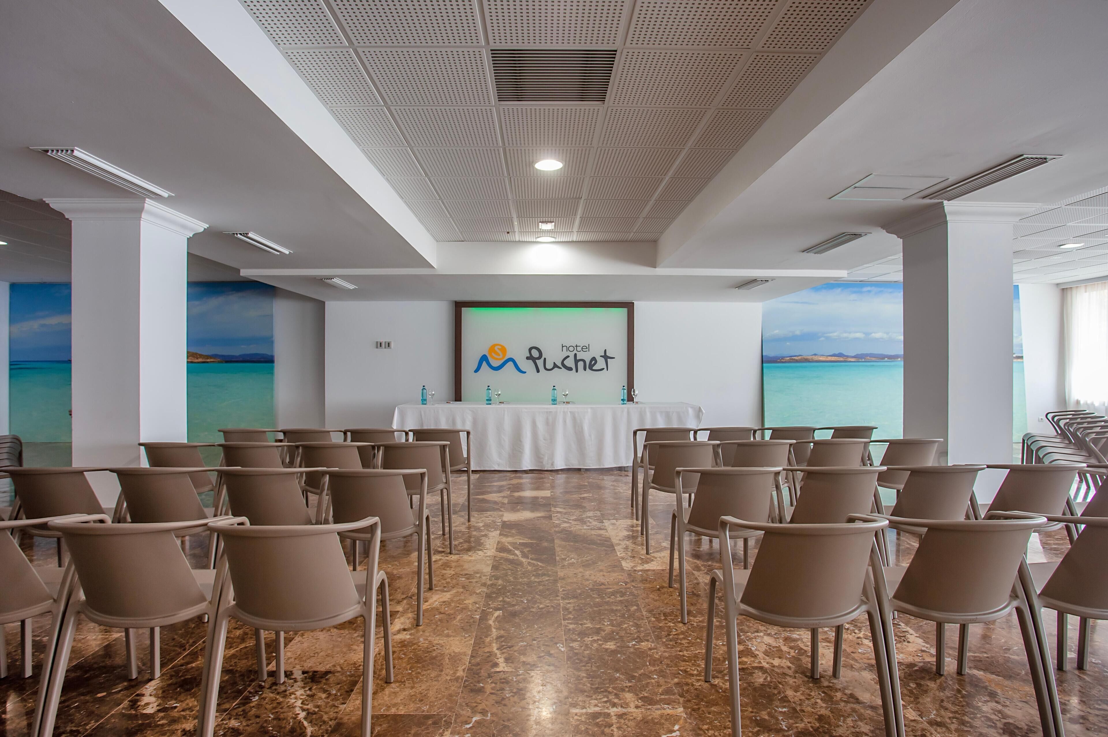 A conference room with a white table, chairs, and a wall with a 'hotel Pushet' sign.