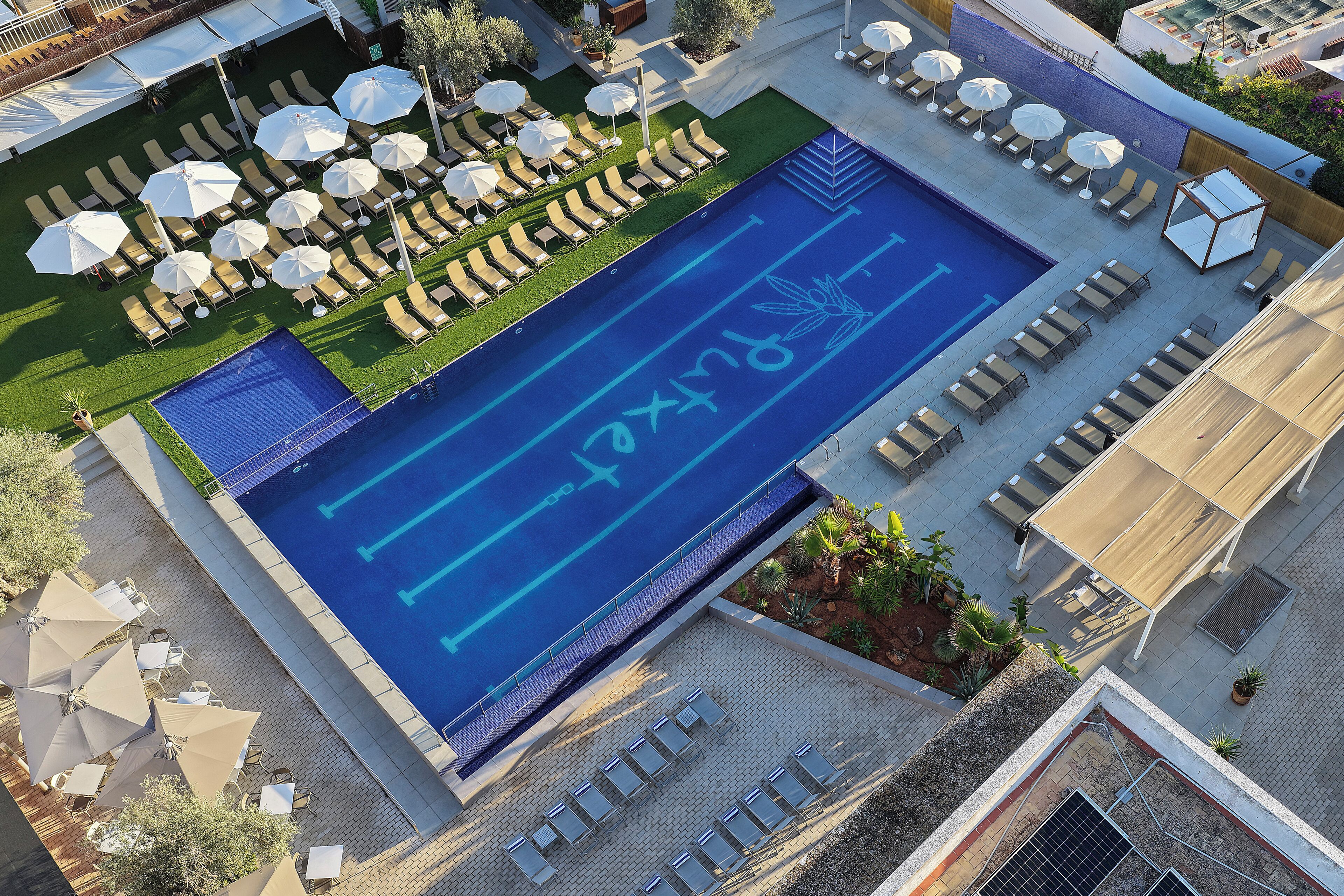 Eine Vogelperspektive auf ein Hotel-Pool-Gelände mit Liegestühlen, Sonnenschirmen und einem Pool mit blauen Markierungen.